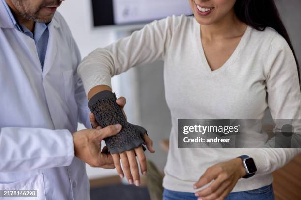 close-up on a woman at the doctor using a 3d printed brace on her wrist - ortopedista imagens e fotografias de stock