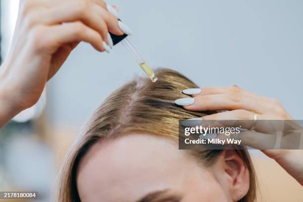 close up woman applies oil to her hair with pipette. beauty caring for scalp and hair. - cuero cabelludo fotografías e imágenes de stock