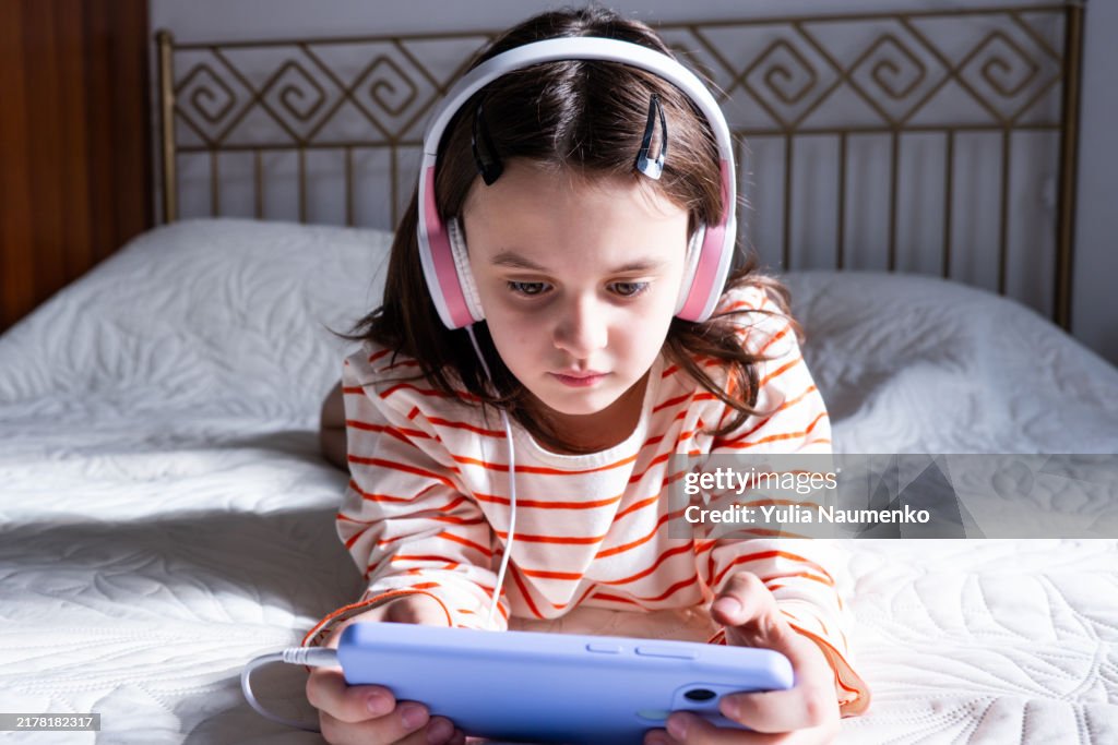 Girl with headphones on the bed. Listen to music