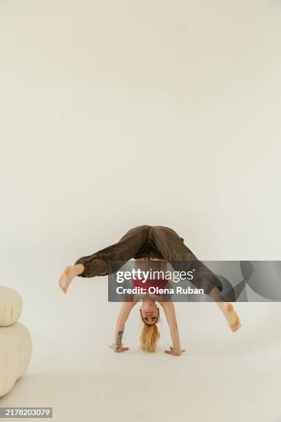 young woman doing handstand in a light setting. - cyclorama telón de fondo fotografías e imágenes de stock