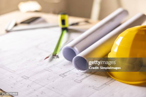 construction blueprints, plan and safety helmet for construction planning with tools, drawings and equipment on table. - blauwdruk stockfoto's en -beelden