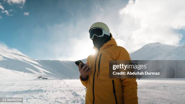 Snowboarder Man Using Smartphone On Snowy Hill, Stockfoto