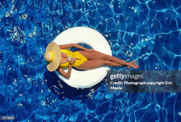 aerial view of a woman in hat with drink in pool - opblaasband stockfoto's en -beelden