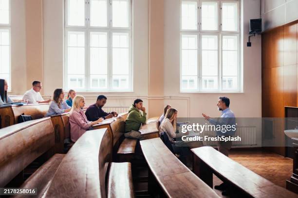 university lecture hall with engaged students and professor - lecture hall stock pictures, royalty-free photos & images