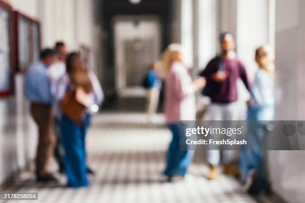 defocused photo of college students engaging in informal conversations in bright corridor - defocussed stock pictures, royalty-free photos & images