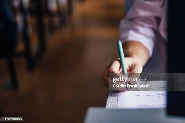 handwriting on paper in a quiet college setting, taking an exam - self reflection man stock pictures, royalty-free photos & images