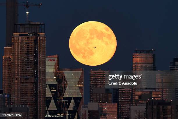 Helicopter flies in front of the full moon in Toronto, Ontario on October 17, 2024.