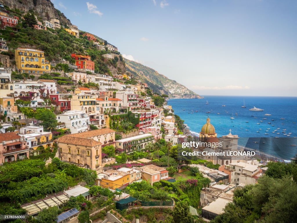 Aerial view of Positano with its colorful houses on the cliffs, lined with trees, the Tyrrhenian Sea, the dome of its church and its crowded beach, Amalfi Coast - UNESCO World Heritage Site - Campania - Mezzogiorno (Southern Italy).