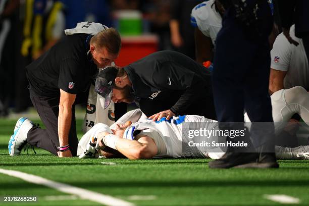 Aidan Hutchinson of the Detroit Lions is tended to by medical staff after injuring his leg while recording a sack on Dak Prescott of the Dallas...