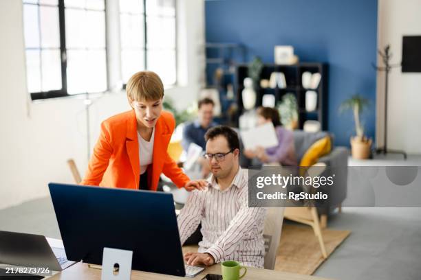 managerin unterstützt ihren mitarbeiter mit down-syndrom - chancengleichheit stock-fotos und bilder