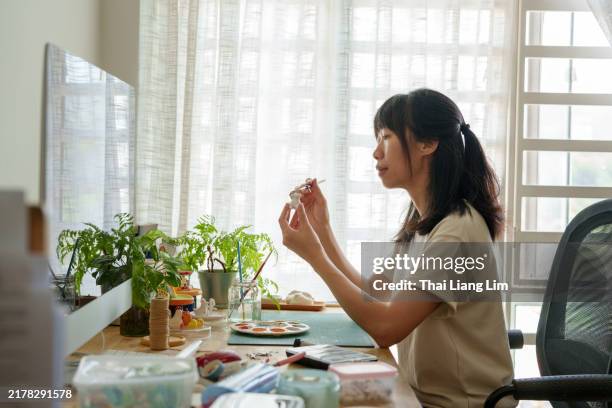 a close-up of a female artist carefully painting on a cute ceramic piece, showcasing her creative artistry. - hobbies stock pictures, royalty-free photos & images