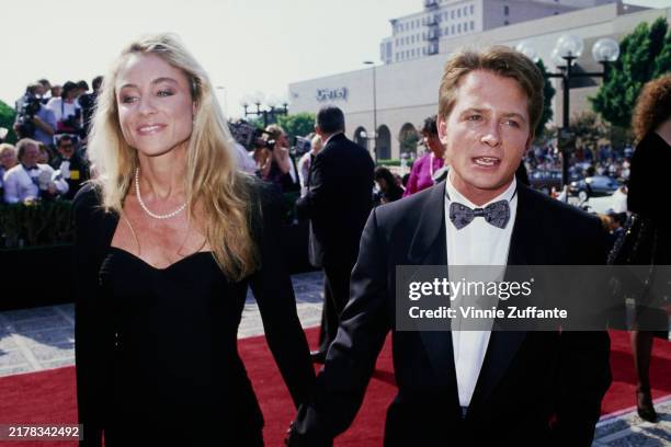 American actress Tracy Pollan, wearing a black outfit with a pearl necklace, and her husband, Canadian actor Michael J Fox, who wears a tuxedo and a...