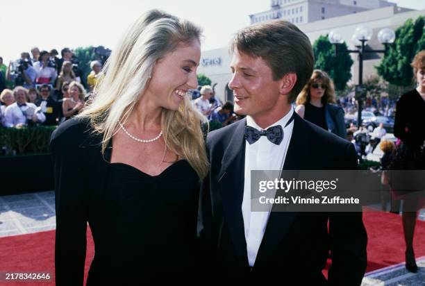 American actress Tracy Pollan, wearing a black outfit with a pearl necklace, and her husband, Canadian actor Michael J Fox, who wears a tuxedo and a...