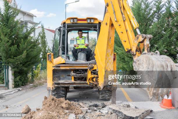 excavadora excavando asfalto en la calle de la ciudad - movimiento de tierras fotografías e imágenes de stock