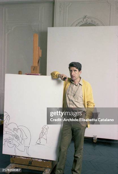 Italian painter Valerio Adami in his studio leaning against one of his canvases, Paris, France, 1980