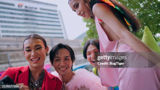 young lgbtqia+ friends talking and holding a rainbow flag outdoors - social justice concept stock pictures, royalty-free photos & images