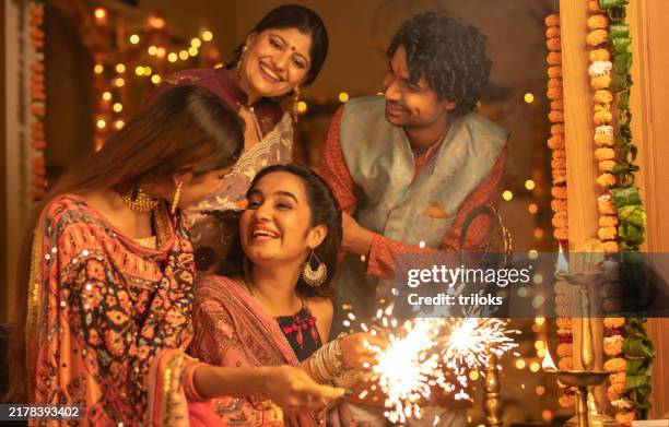 young family celebrating diwali festival at home - diwali stock pictures, royalty-free photos & images