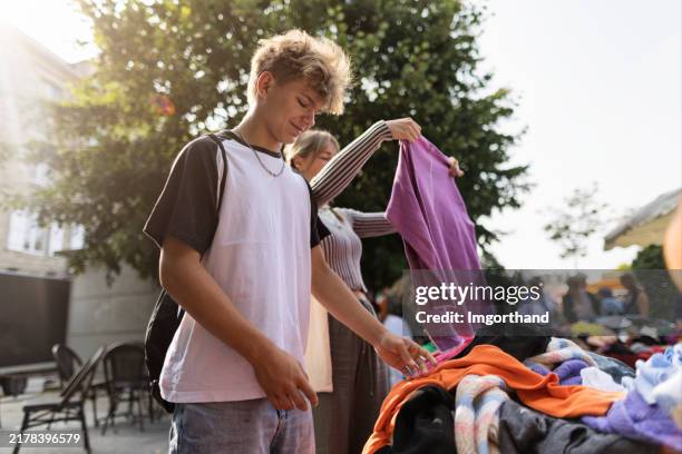 teenagers browsing second-hand clothes in dinan market. - kringloopwinkel stockfoto's en -beelden