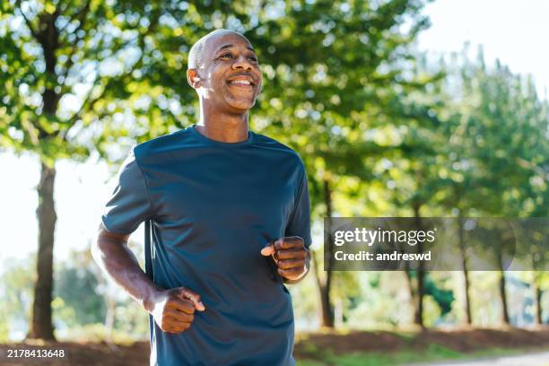 portrait of a mature man running in the public park - cardiovasculaire training stockfoto's en -beelden