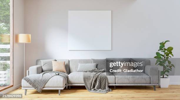 un salon moderne avec un canapé gris et une décoration, devant un fond mural blanc avec un blanc, une toile vierge avec un espace de copie, des fenêtres avec vue sur le patio d’un côté - flouté photos et images de collection