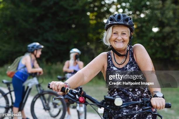 portrait of beautiful senior cyclist on bike tour in nature. older woman on low impact route riding electric bikes. - cholesterol stockfoto's en -beelden