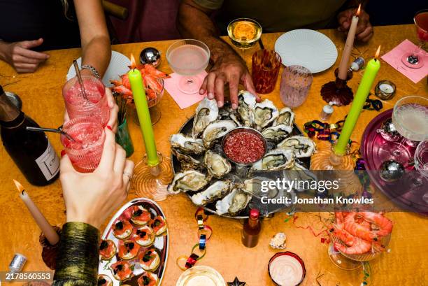 high angle view friends toasting cocktails at table with oysters for new year's eve celebration - seafood stock pictures, royalty-free photos & images