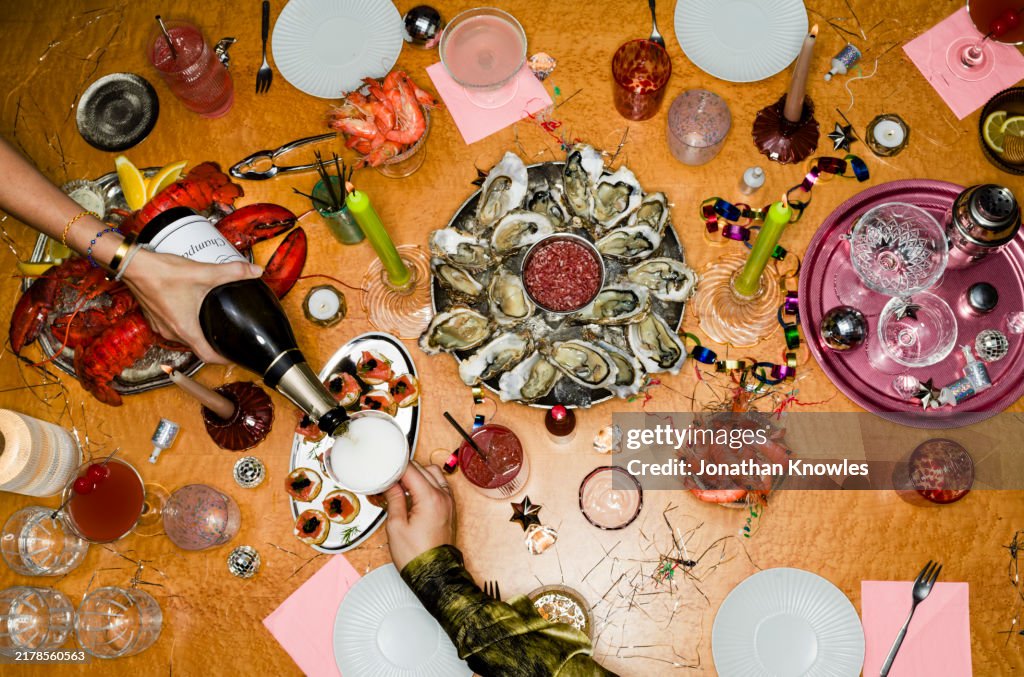 View From Above Woman Pouring Champagne At Table With Oysters For New Year's Eve Party