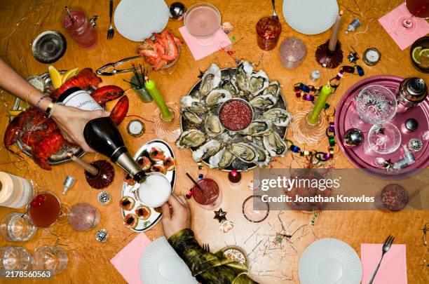 view from above woman pouring champagne at table with oysters for new year's eve party - appetizer stock pictures, royalty-free photos & images
