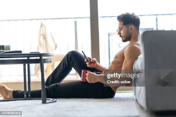 homme musclé à la taille nue surfant avec son téléphone à la main - représentation masculine photos et images de collection