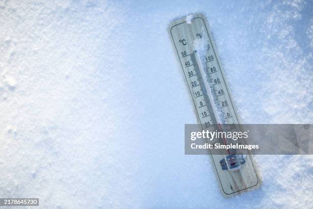 the thermometer on the snow shows low temperatures well below zero. extreme winter freezing weather. - thermometer stockfoto's en -beelden