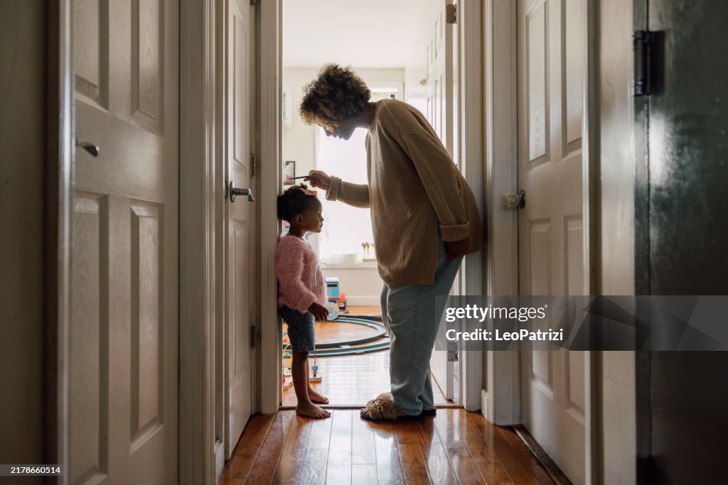 Mère mesurant la taille de sa fille et marquant sur le mur à la maison