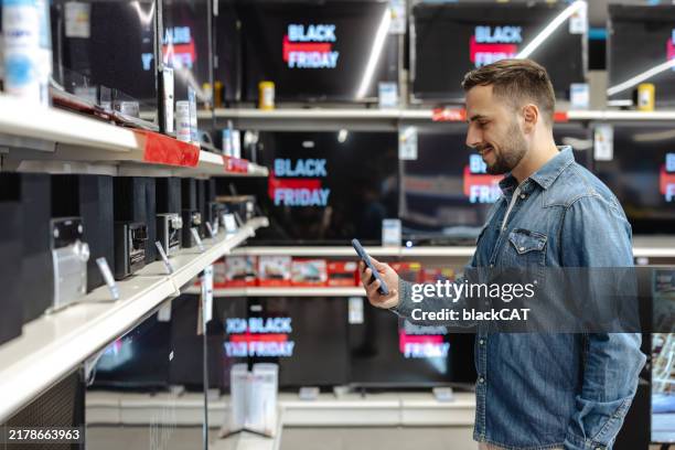 young man shopping for electronics during a black friday sale - black friday bildbanksfoton och bilder