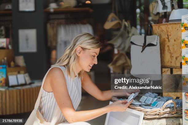 beautiful young woman is enjoying shopping at the souvenir shop - gift shop stock pictures, royalty-free photos & images