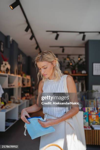 beautiful young woman is enjoying shopping at the souvenir shop - gift shop stock pictures, royalty-free photos & images