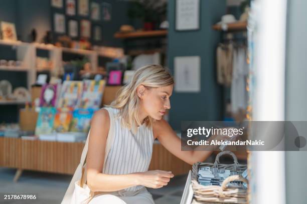 beautiful young woman is enjoying shopping at the souvenir shop - gift shop stock pictures, royalty-free photos & images