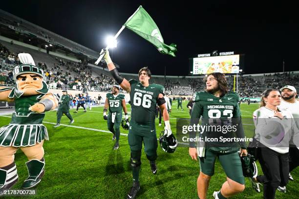 Michigan State Spartans offensive lineman Ashton Lepo raises a Spartan flag following a college football game between the Michigan State Spartans and...