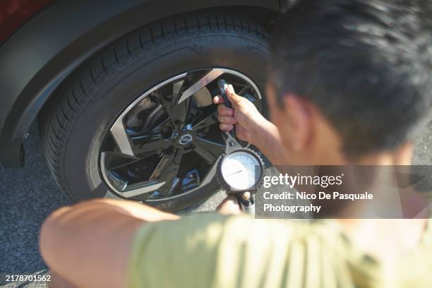 high angle view of man inflating car tire - compressor stock pictures, royalty-free photos & images
