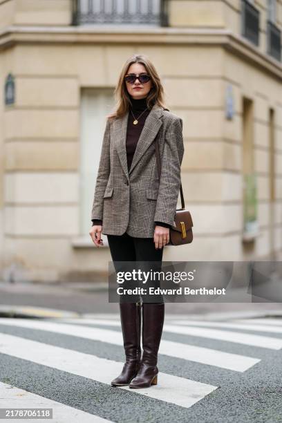 Segolene Hyppolite wears brown Jimmy Fairly sunglasses, gold necklace, grey checked Maje blazer jacket, a dark brown Maje turtleneck pullover, black...