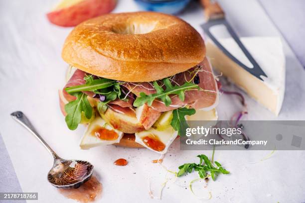 bagel sandwich with brie, prosciutto and apple - brie stock pictures, royalty-free photos & images