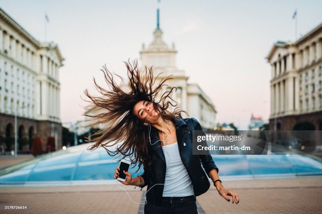 Young girl dancing to the music in the city