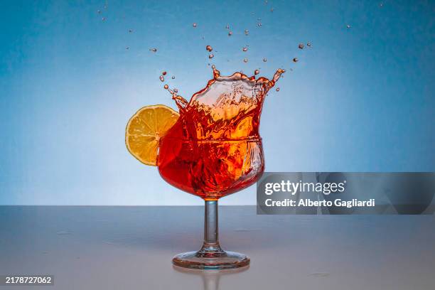 ice cube falling into a negroni splashing - cocktail stock pictures, royalty-free photos & images