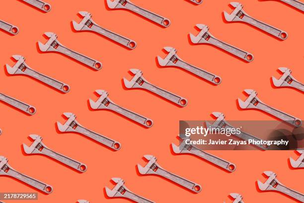 many adjustable wrenches on red background - verstellbarer schraubenschlüssel stock-fotos und bilder