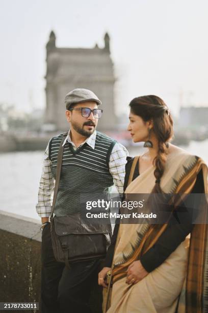 coppia di metà adulto assorta in una conversazione al gateway of india, mumbai - borsa a tracolla foto e immagini stock