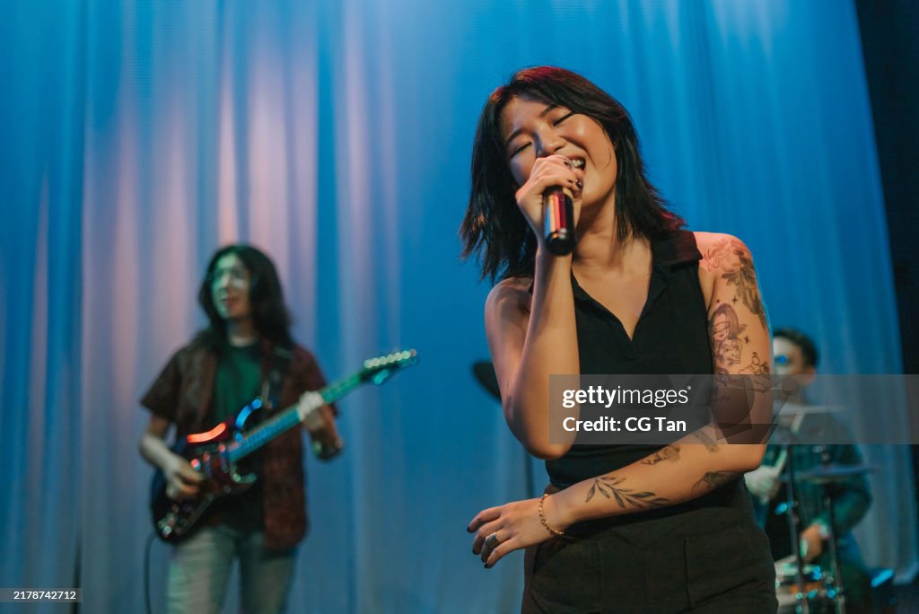 Young Asian chinese lead singer and live band Multiracial group performance on stage