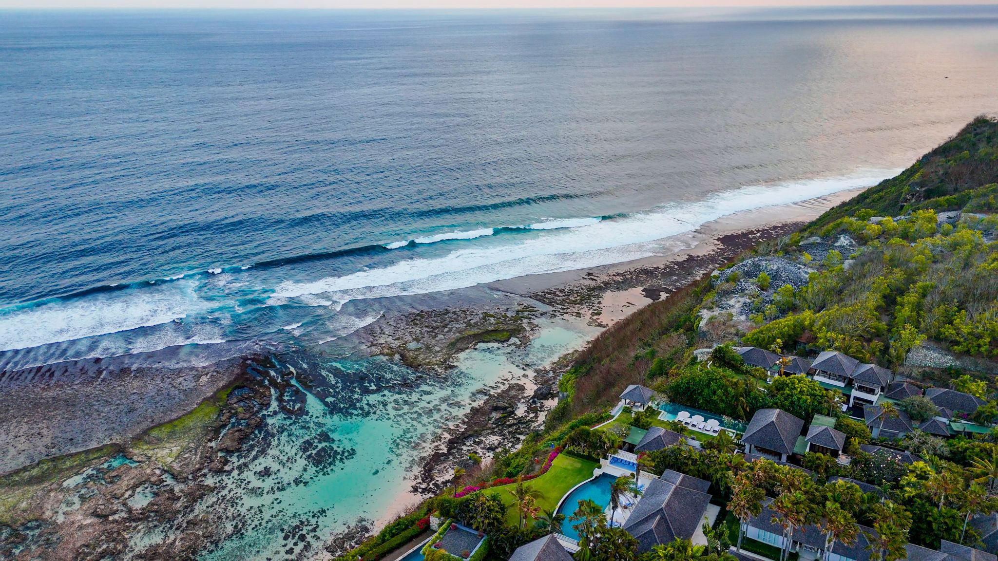 Aerial sunset view of Badung - Uluwatu cliffs on Bali Island, Indian Ocean coast, Indonesia, Sunset over a white sandy beach along the cliff in Bali, Sunset in Bukit, Sun loungers on Bali beach Aerial sunset view of Badung - Uluwatu cliffs on Bali Island, Indian Ocean coast, Indonesia, Sunset over a white sandy beach along the cliff in Bali, Sunset in Bukit, Sun loungers on Bali beach