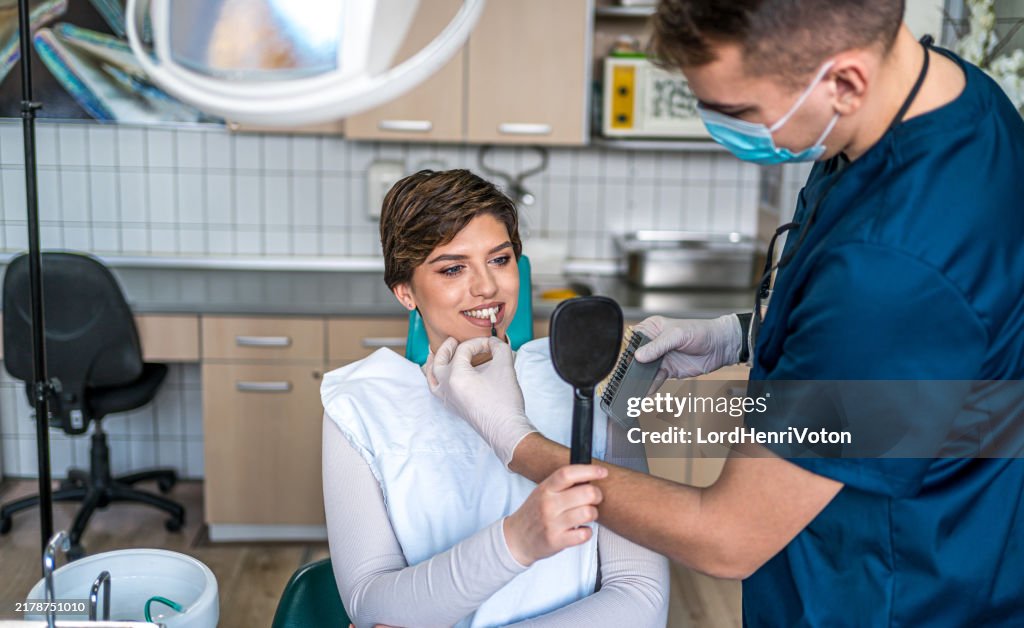 Dentista che confronta la tonalità dei denti del paziente con i campioni
