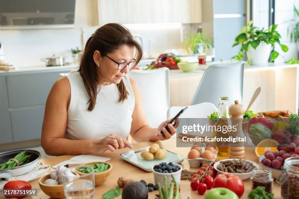 woman in kitchen using weight scale to plan well balanced diet. - carbohidrato fotografías e imágenes de stock