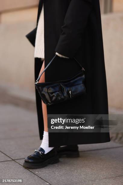 Sophia Geiss is seen wearing an ankle-length, oversized black coat from 032c; an oversized knit pullover from Black Palms underneath; a rectangular...