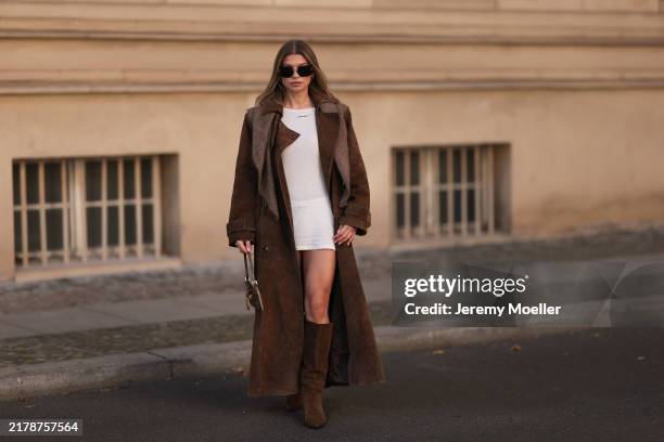 Sophia Geiss is seen wearing large rectangular rimless sunglasses with golden details from Miu Miu; two different-sized gold hoop earrings; a silver...