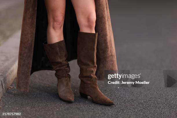 Sophia Geiss is seen wearing an ankle-length brown suede trench coat from Ducie London, and pointed brown suede slouch boots with short heels from...